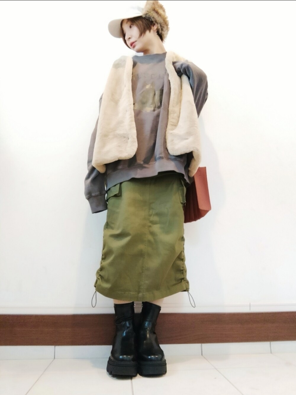 ブラウン系のスウェット、ベージュ系のトートバッグ、グリーン系のスカートを着用したレディースの秋コーディネートの2枚目の写真