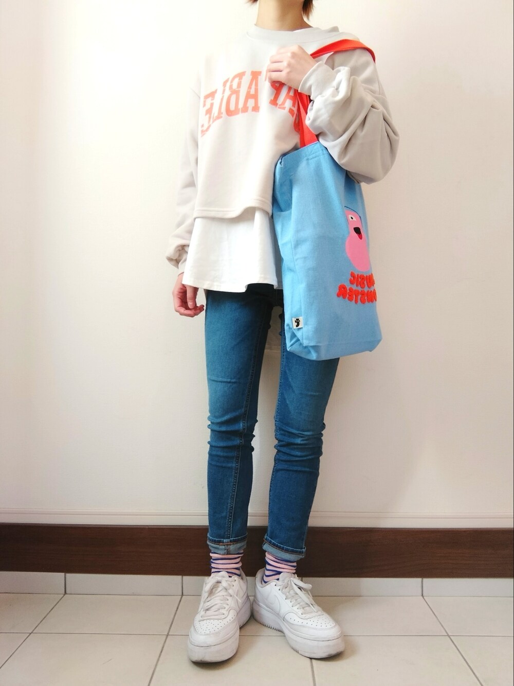 グレー系のスウェット、ブルー系のトートバッグ、ブルー系のデニムパンツを着用したレディースの冬コーディネートの2枚目の写真