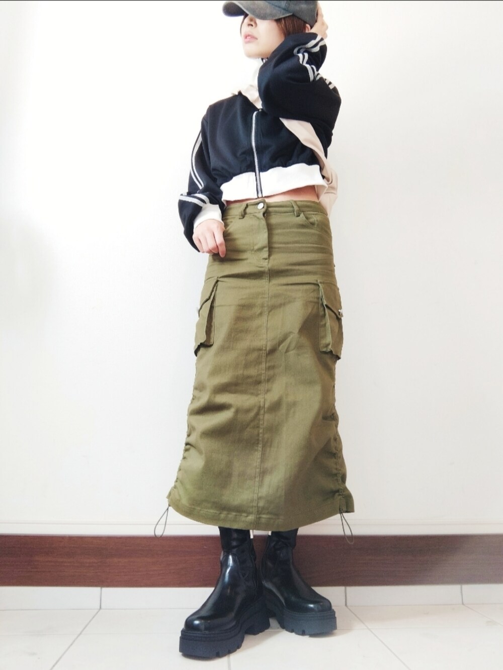 ブラック系のジャージ、グリーン系のスカート、ブラック系のブーツを着用したレディースの秋コーディネートの2枚目の写真