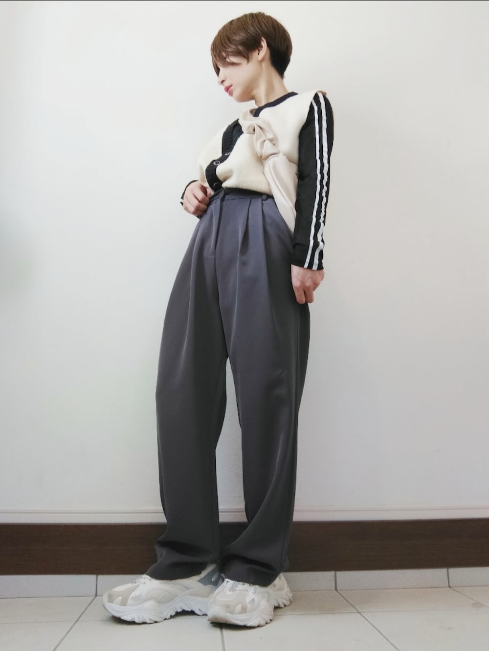 グレー系のスラックス、ホワイト系のスニーカー、ホワイト系のショルダーバッグを着用したレディースの秋コーディネートの2枚目の写真