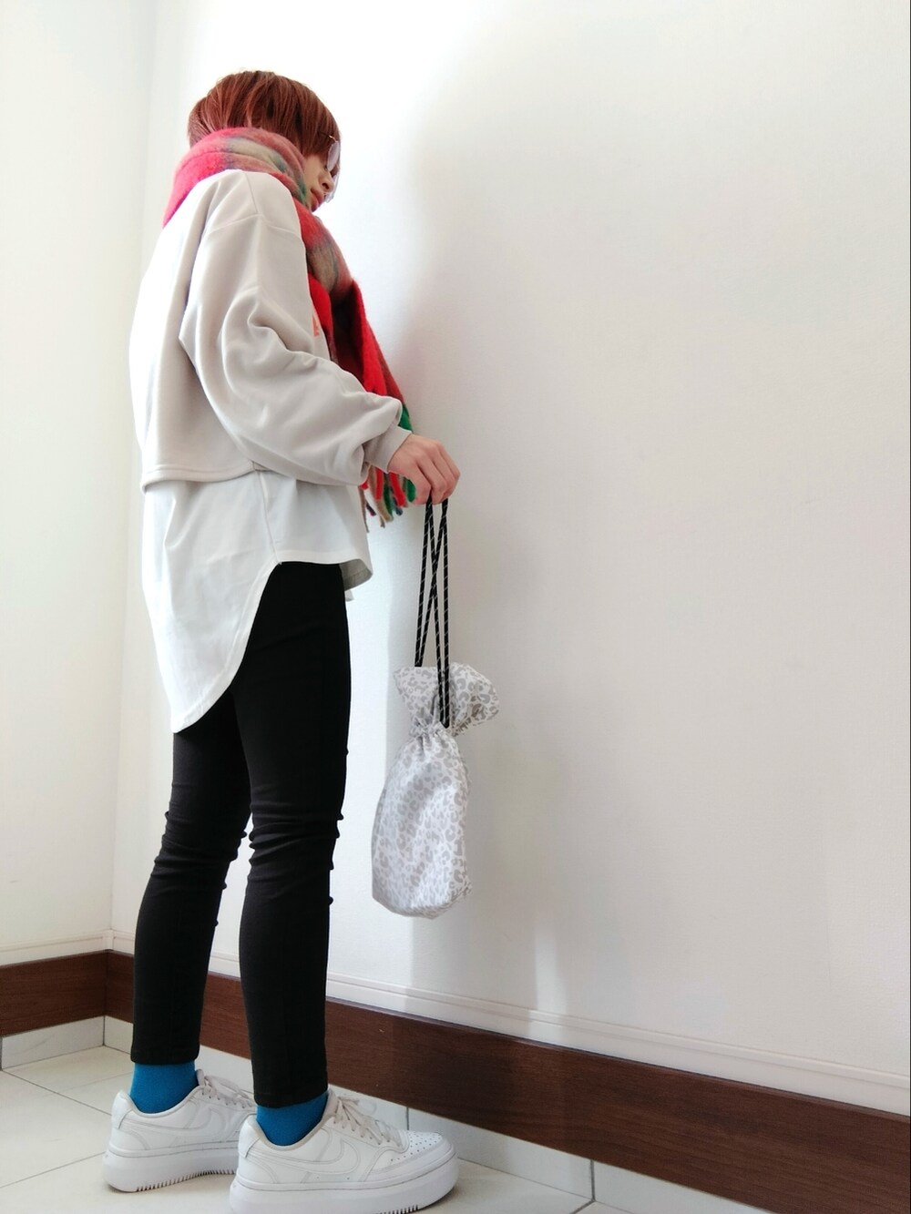 グレー系のスウェット、ホワイト系のショルダーバッグ、ホワイト系のスニーカーを着用したレディースの冬コーディネートの2枚目の写真