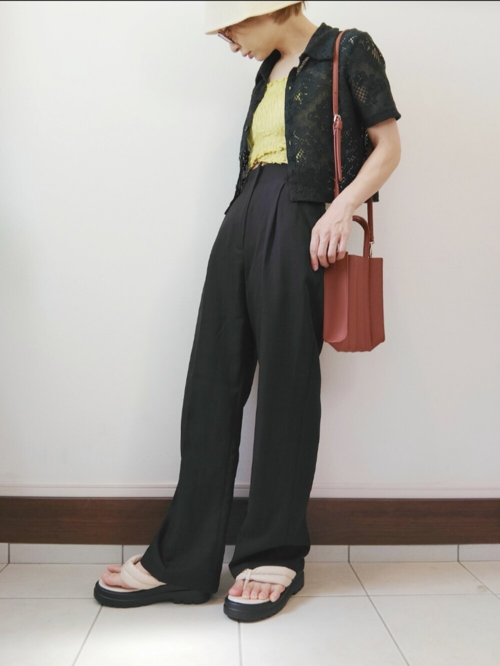 グリーン系のキャミソール、ベージュ系のトートバッグ、ブラック系のスラックスを着用したレディースの夏コーディネートの2枚目の写真