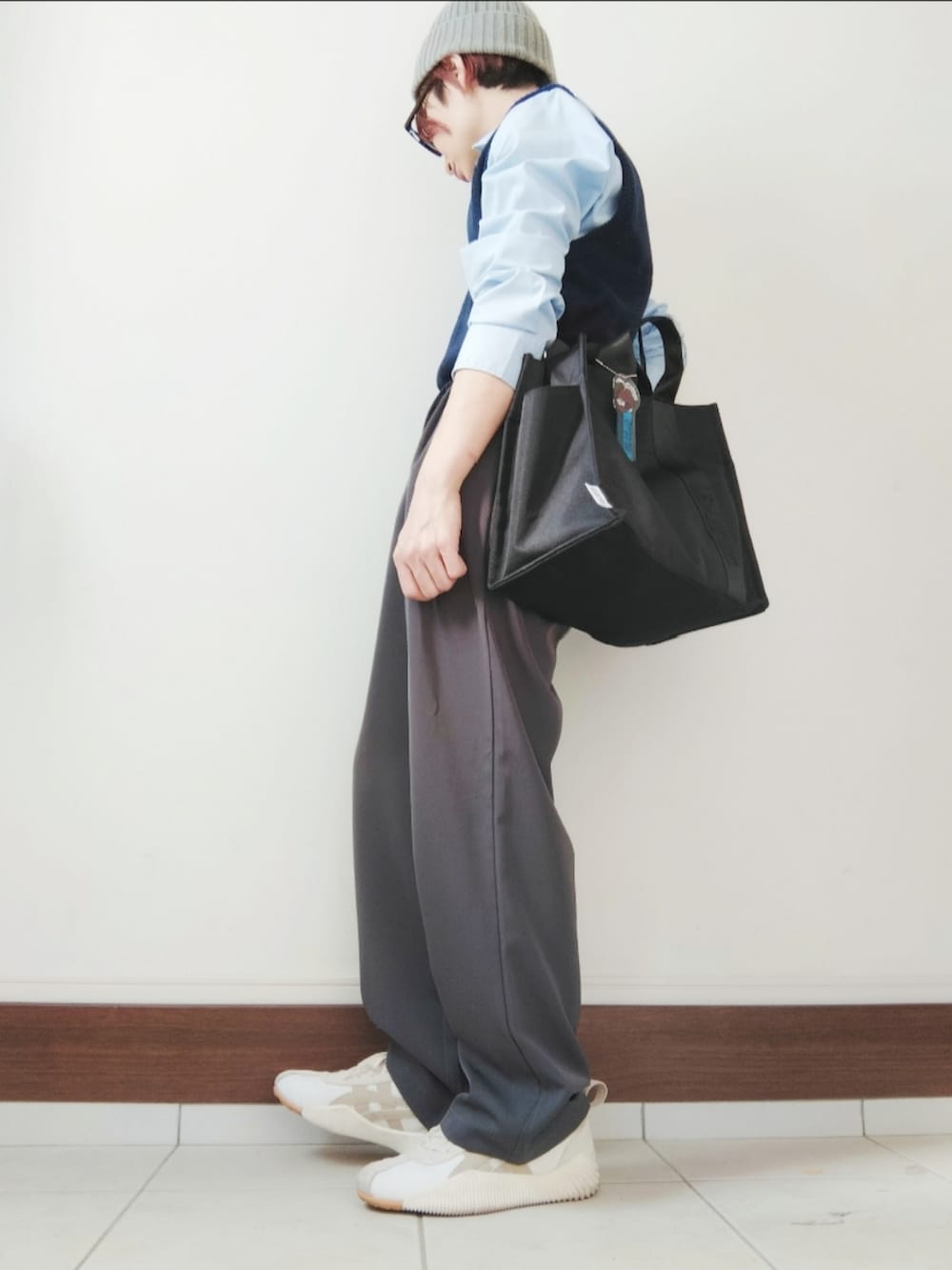 ブルー系のベスト、ブラック系のトートバッグ、グレー系のスラックスを着用したレディースの冬コーディネートの2枚目の写真