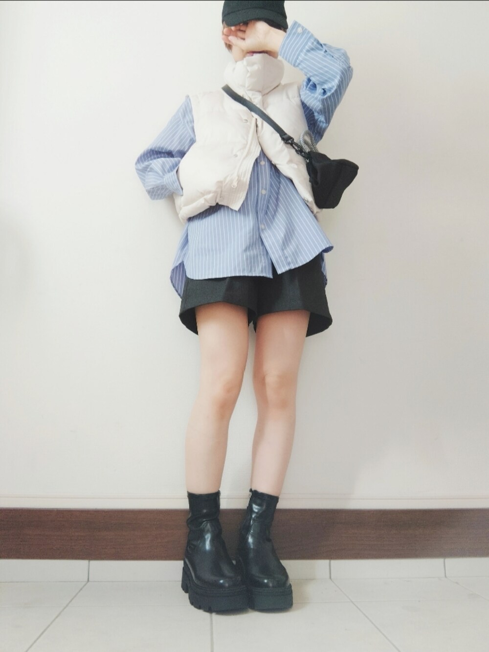 ホワイト系のダウンベスト、ブラック系のショルダーバッグ、ブラック系のブーツを着用したレディースの秋コーディネートの2枚目の写真