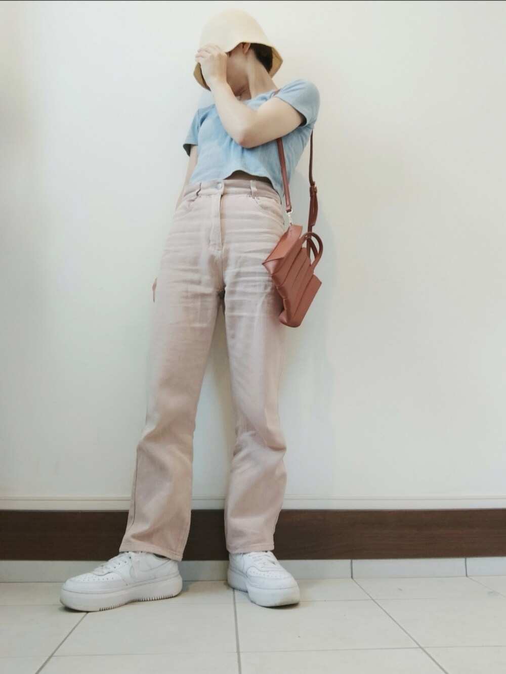 ベージュ系のトートバッグ、ピンク系のデニムパンツ、ホワイト系のスニーカーを着用したレディースの夏コーディネートの2枚目の写真