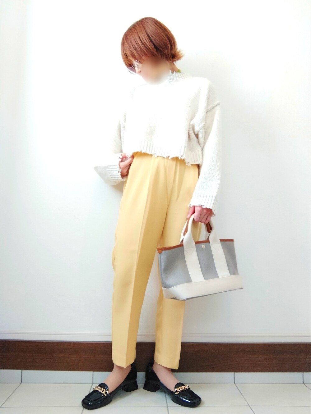 グレー系のトートバッグ、ホワイト系のニット/セーター、ブラック系のパンプスを着用したレディースの冬コーディネートの2枚目の写真