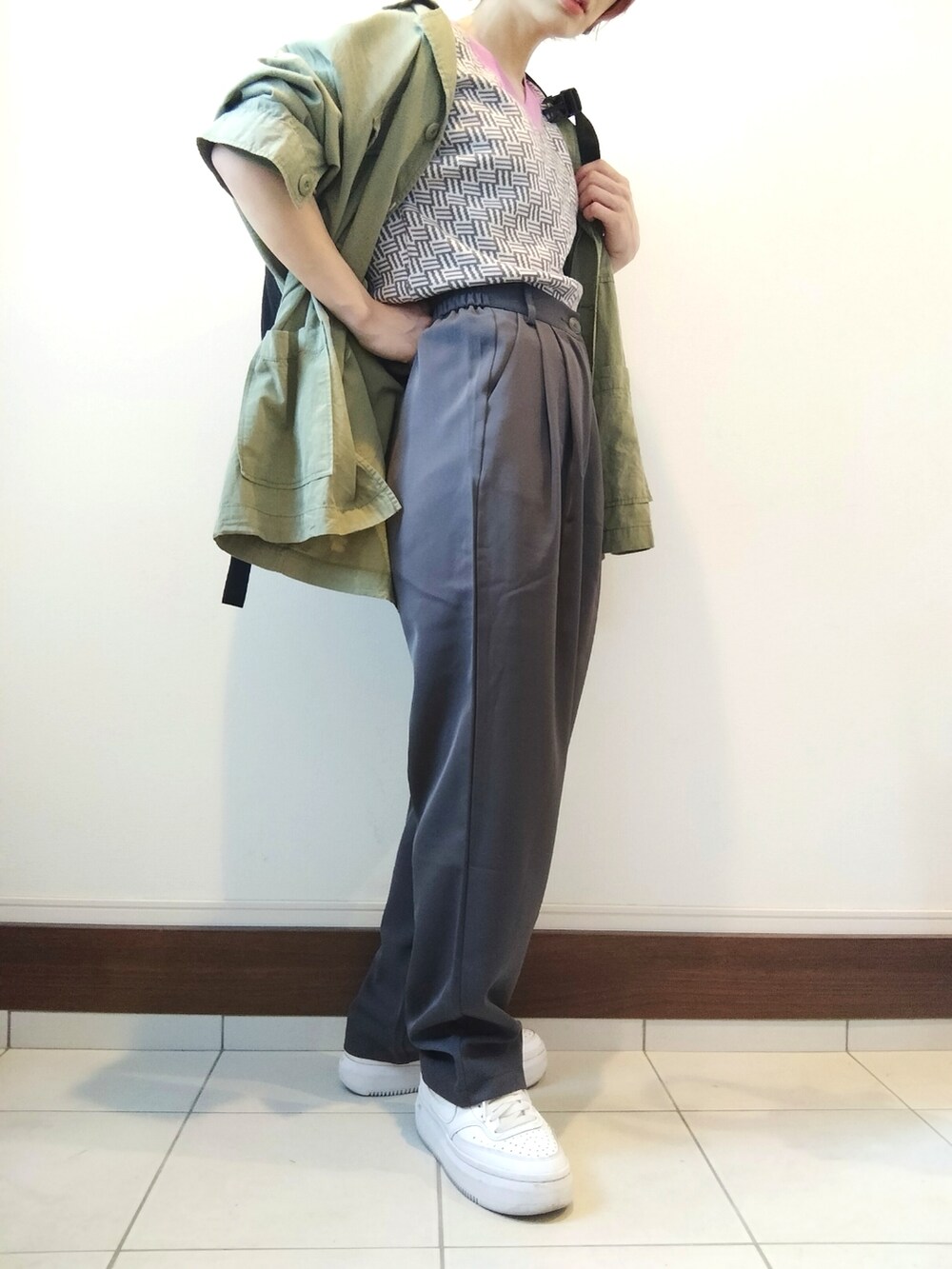 グレー系のベスト、グリーン系のシャツ/ブラウス、グレー系のスラックスを着用したレディースの春コーディネートの2枚目の写真