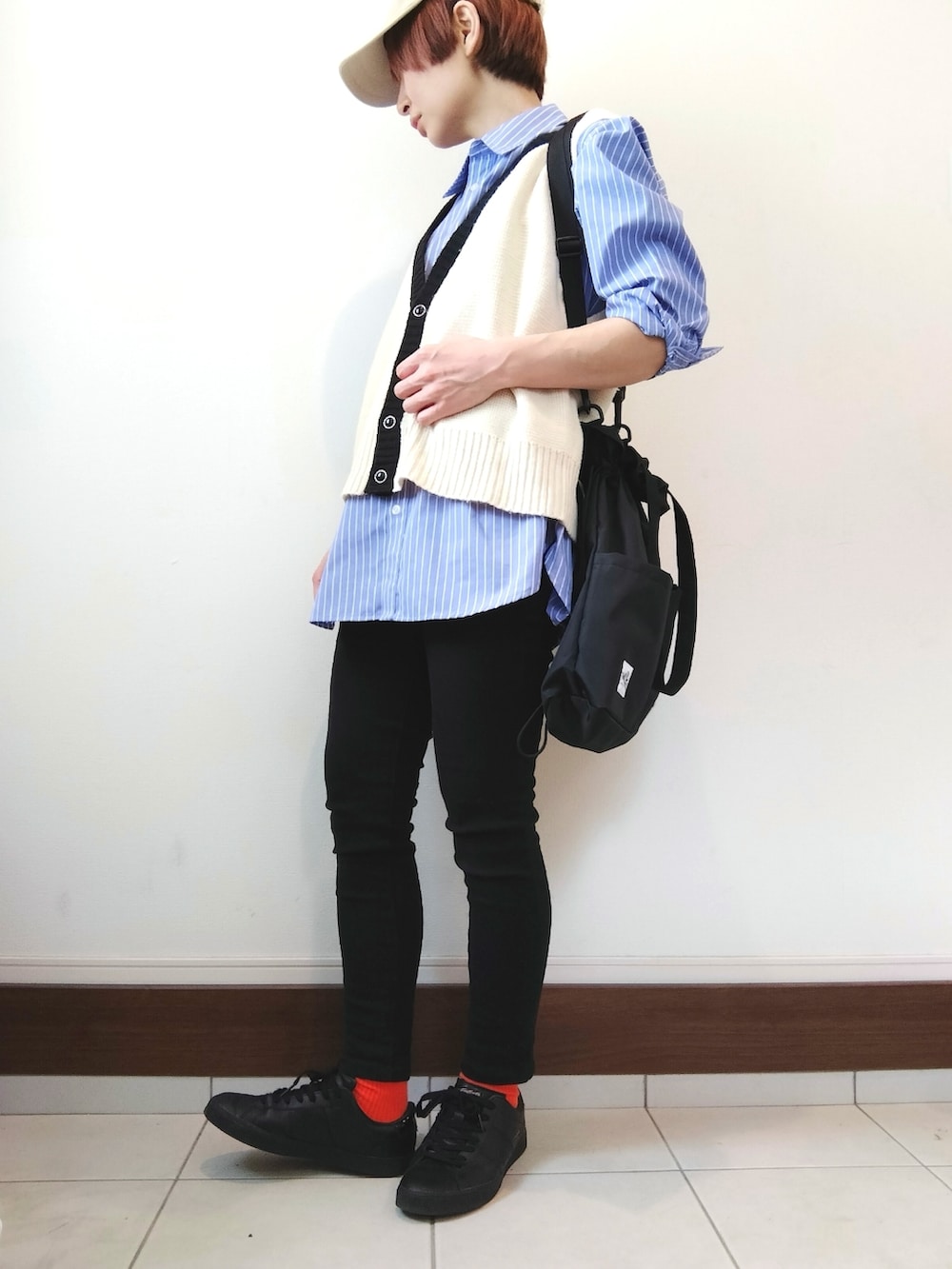 ホワイト系のベスト、ブルー系のシャツ/ブラウス、ブラック系のショルダーバッグを着用したレディースの春コーディネートの2枚目の写真