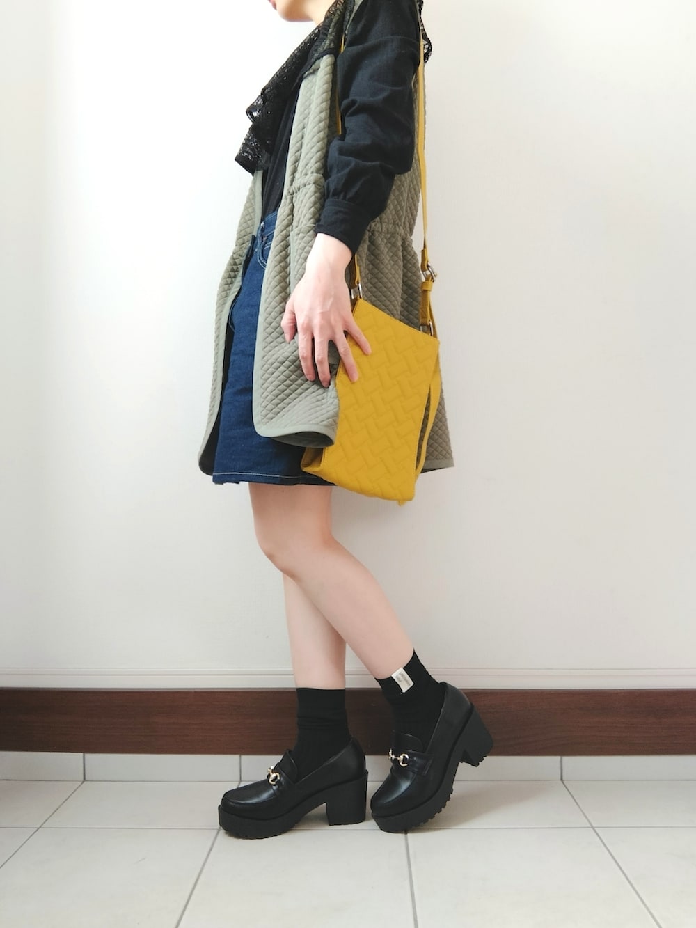 グリーン系のベスト、ブラック系のTシャツ/カットソー、ブルー系のデニムスカートを着用したレディースの春コーディネートの2枚目の写真