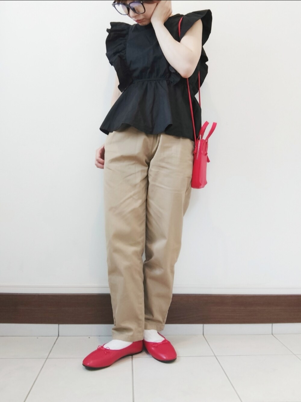 ベージュ系のチノパンツ、レッド系のバレエシューズ、レッド系のショルダーバッグを着用したレディースの夏コーディネートの2枚目の写真