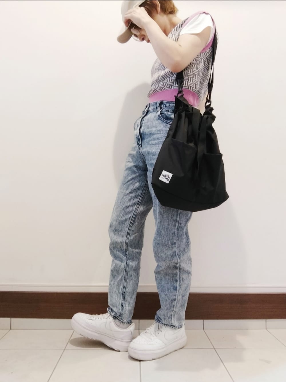 グレー系のベスト、ブラック系のショルダーバッグ、ホワイト系のスニーカーを着用したレディースの夏コーディネートの2枚目の写真