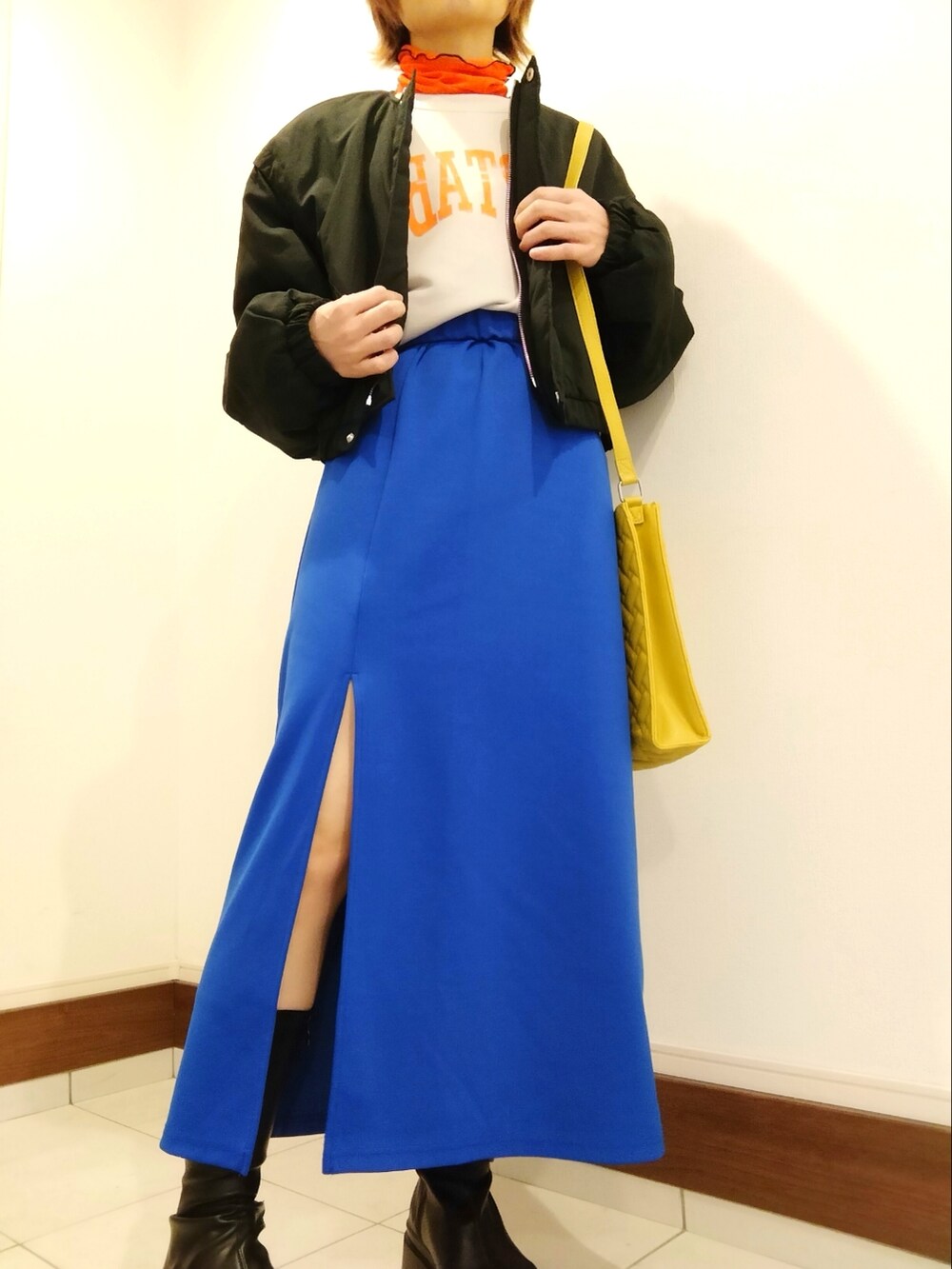 ブラック系のノーカラージャケット、イエロー系のショルダーバッグ、ブルー系のスカートを着用したレディースの冬コーディネートの2枚目の写真