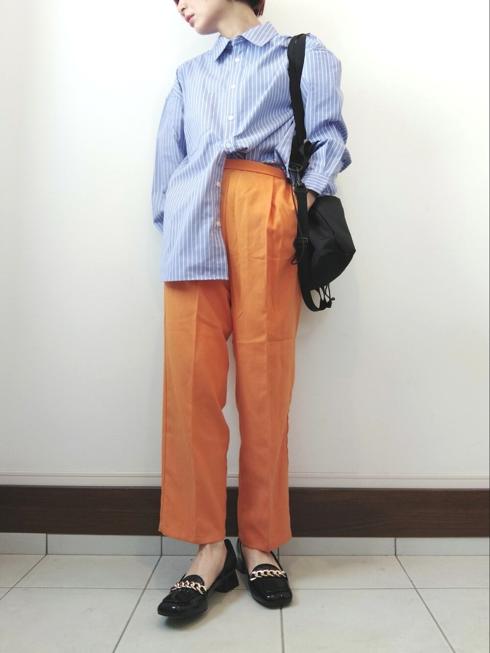 ブルー系のシャツ/ブラウス、ブラック系のショルダーバッグ、オレンジ系のスラックスを着用したレディースの春コーディネートの2枚目の写真