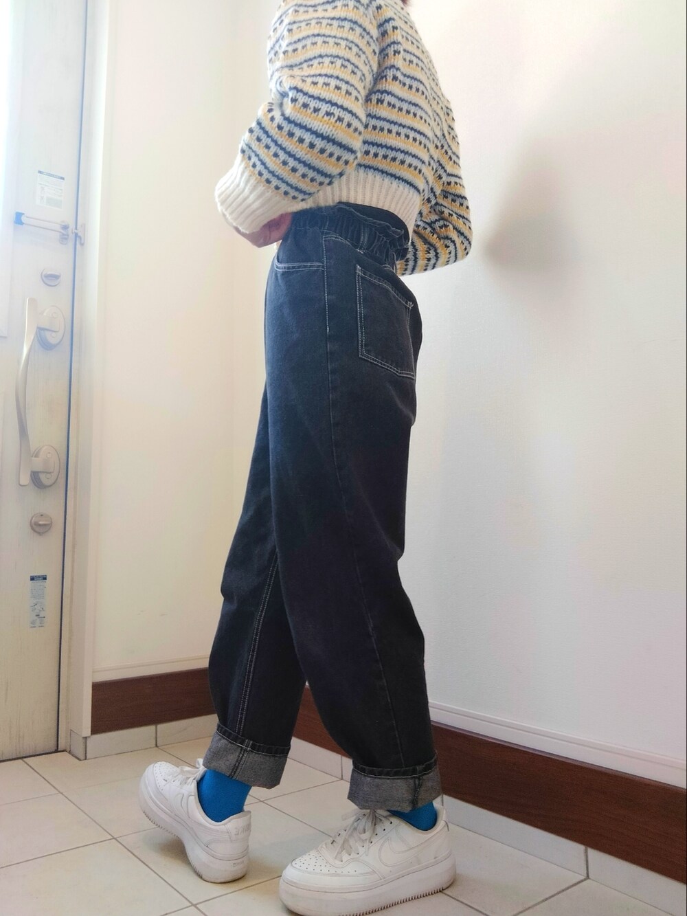 ホワイト系のカーディガン/ボレロ、ブラック系のデニムパンツ、ホワイト系のスニーカーを着用したレディースの冬コーディネートの2枚目の写真