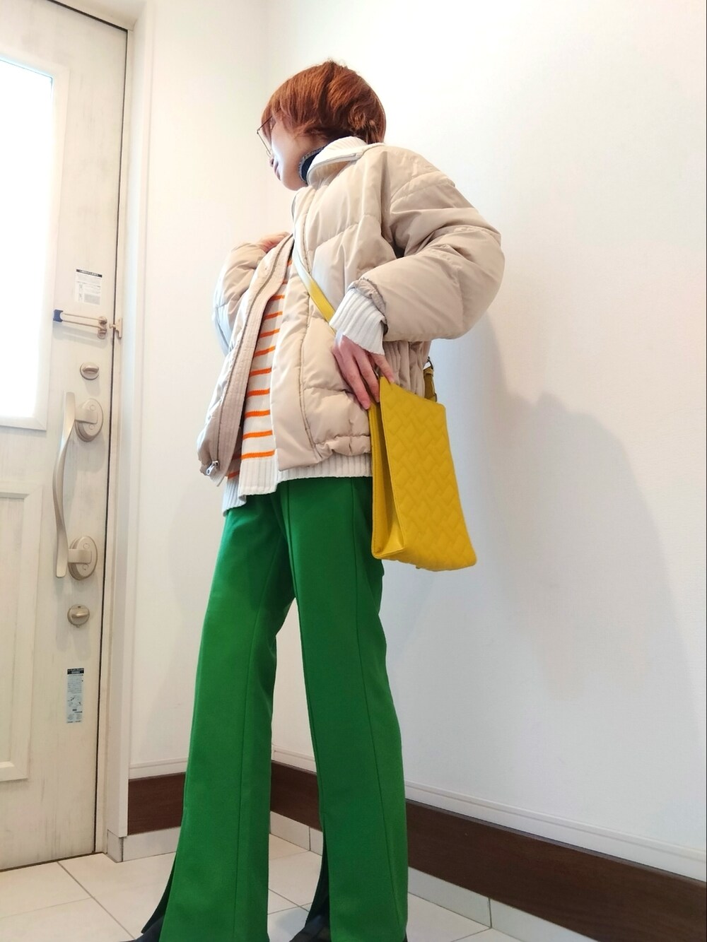 グリーン系のその他パンツ、ベージュ系のダウンジャケット/コート、イエロー系のショルダーバッグを着用したレディースの冬コーディネートの2枚目の写真