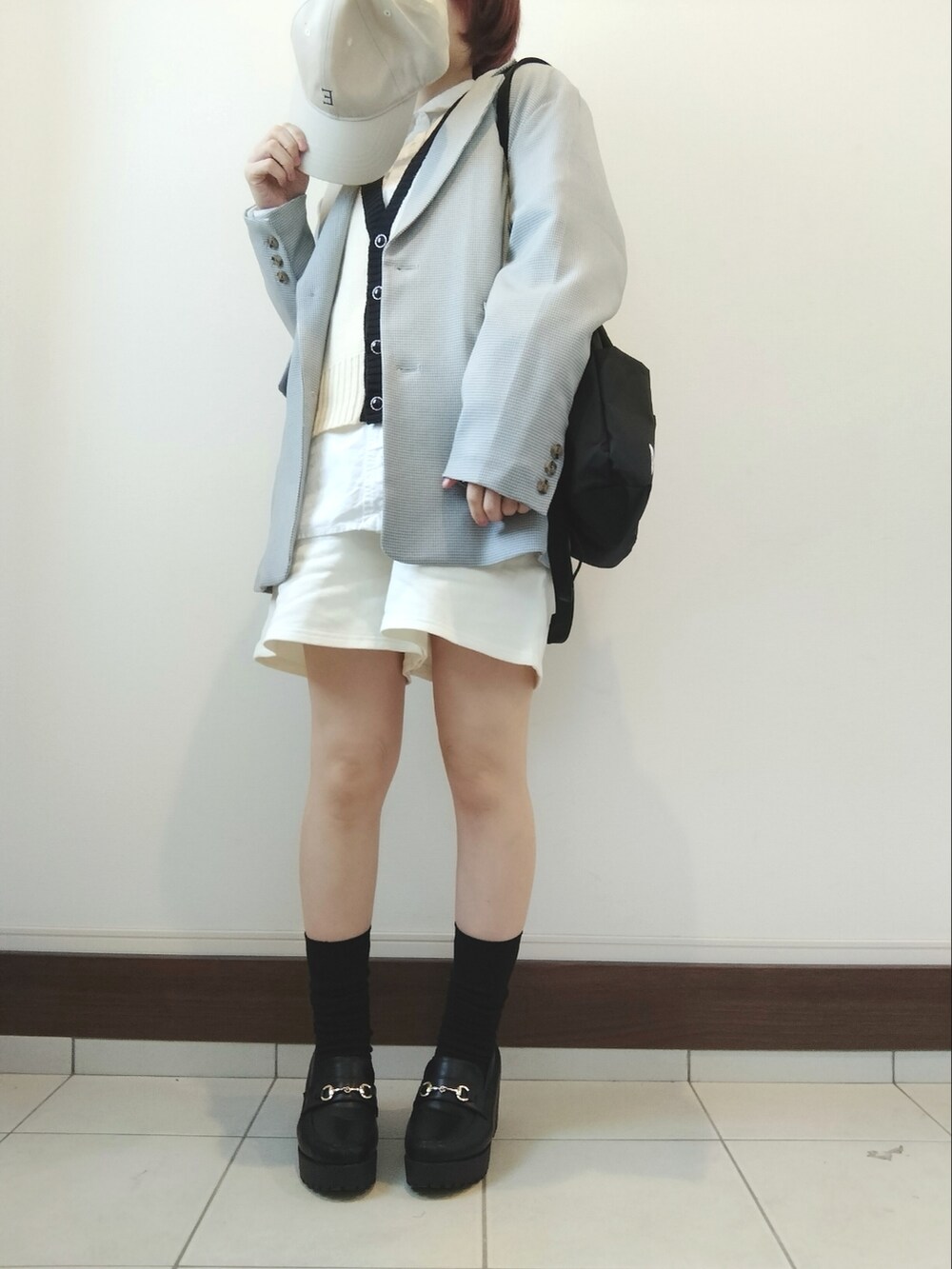 ブラウン系のテーラードジャケット、ホワイト系のベスト、ブラック系のショルダーバッグを着用したレディースの冬コーディネートの2枚目の写真