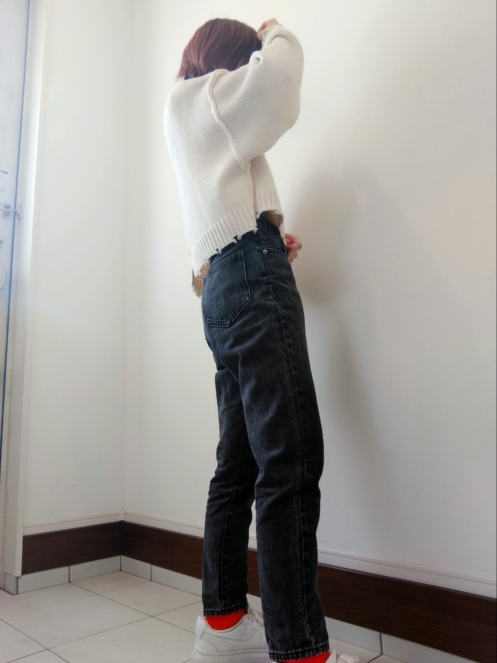 ホワイト系のニット/セーター、ブラック系のデニムパンツ、ホワイト系のスニーカーを着用したレディースの冬コーディネートの2枚目の写真