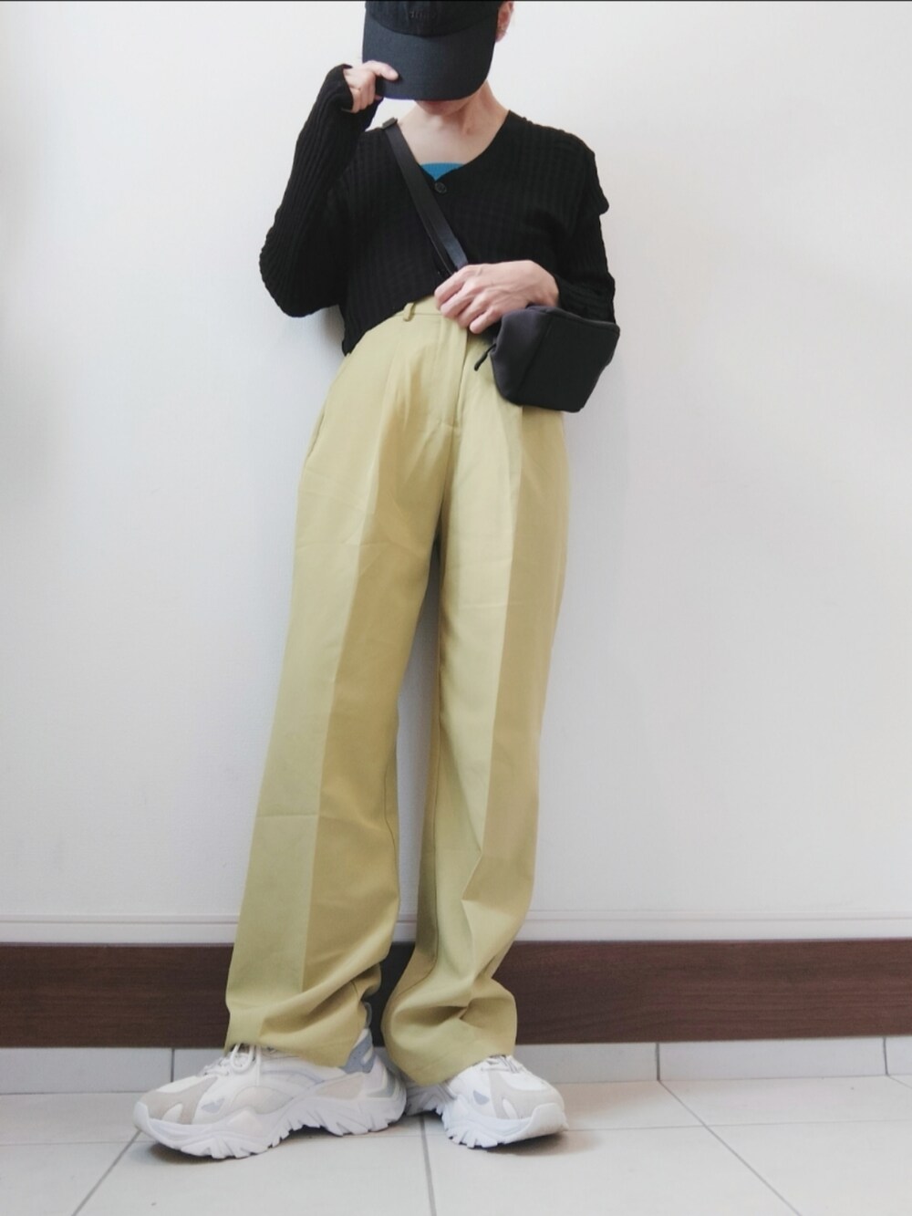 ブラック系のショルダーバッグ、イエロー系のスラックス、ホワイト系のスニーカーを着用したレディースの夏コーディネートの2枚目の写真