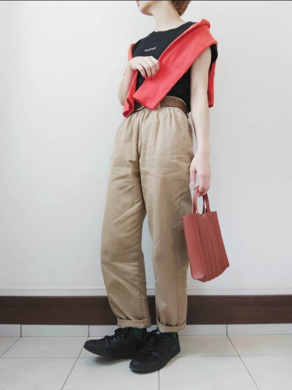 ブラック系のTシャツ/カットソー、オレンジ系のカーディガン/ボレロ、ベージュ系のチノパンツを着用したレディースの春コーディネートの2枚目の写真