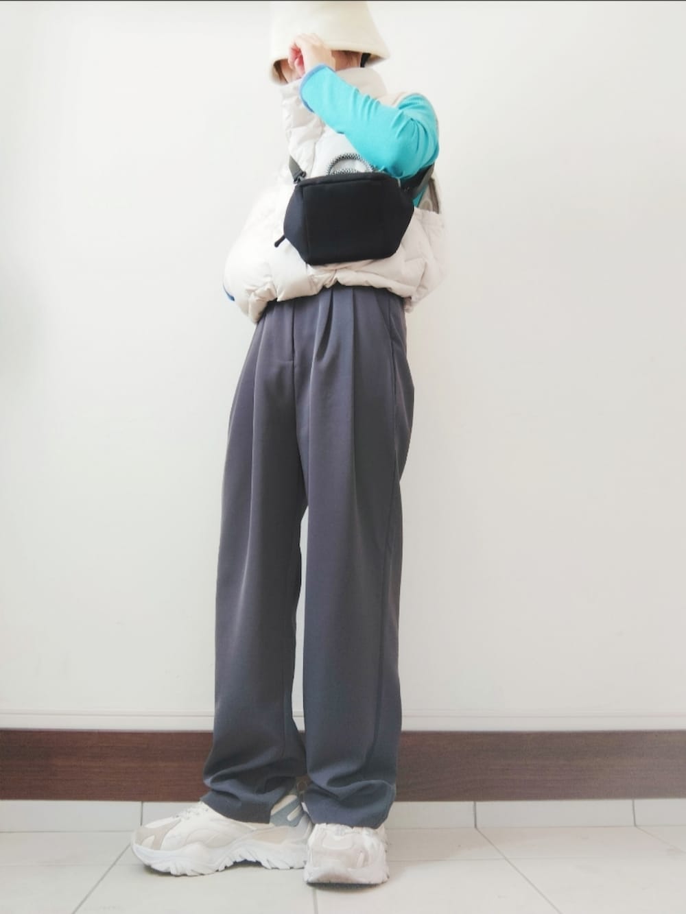 ブラック系のショルダーバッグ、ホワイト系のダウンベスト、ブルー系のTシャツ/カットソーを着用したレディースの秋コーディネートの2枚目の写真