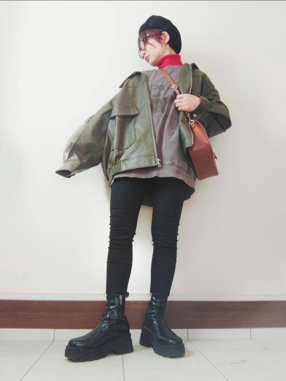 ブラウン系のスウェット、グリーン系のライダースジャケット、ブラック系のデニムパンツを着用したレディースの冬コーディネートの2枚目の写真