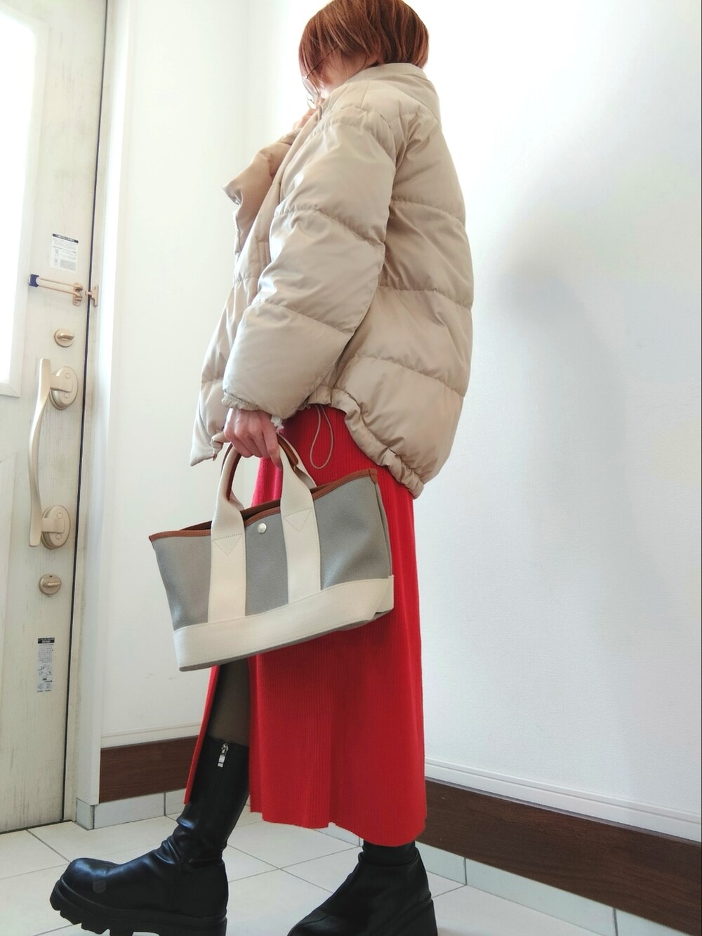 ベージュ系のダウンジャケット/コート、レッド系のスカート、グレー系のトートバッグを着用したレディースの冬コーディネートの2枚目の写真
