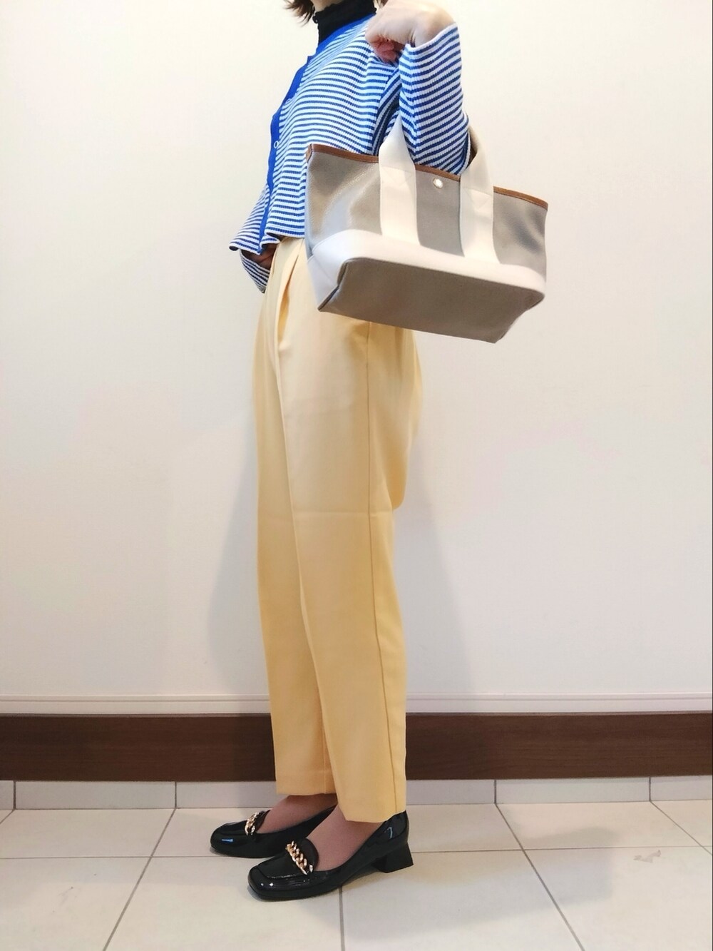 イエロー系のスラックス、ブラック系のパンプスを着用したレディースの冬コーディネートの2枚目の写真