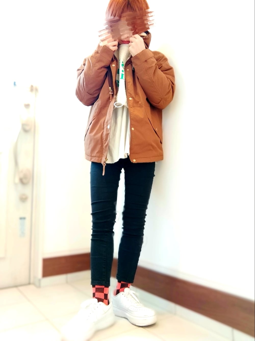 ホワイト系のスウェット、ブラウン系のマウンテンパーカー、ブラック系のデニムパンツを着用したレディースの冬コーディネートの2枚目の写真