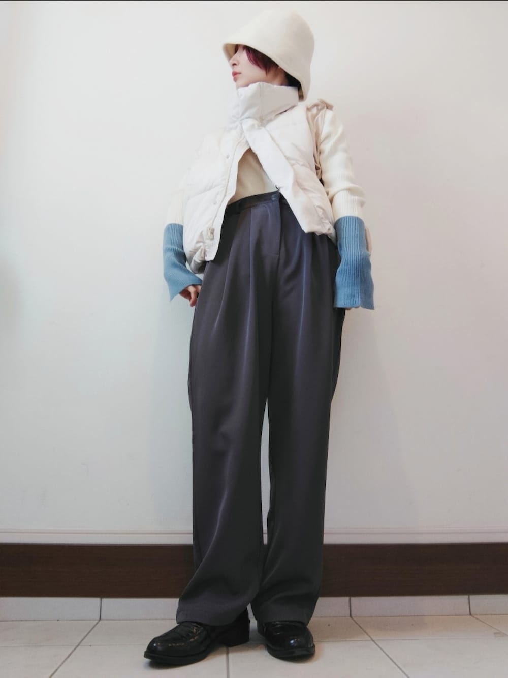 ホワイト系のニット/セーター、ホワイト系のダウンベスト、グレー系のスラックスを着用したレディースの冬コーディネートの2枚目の写真