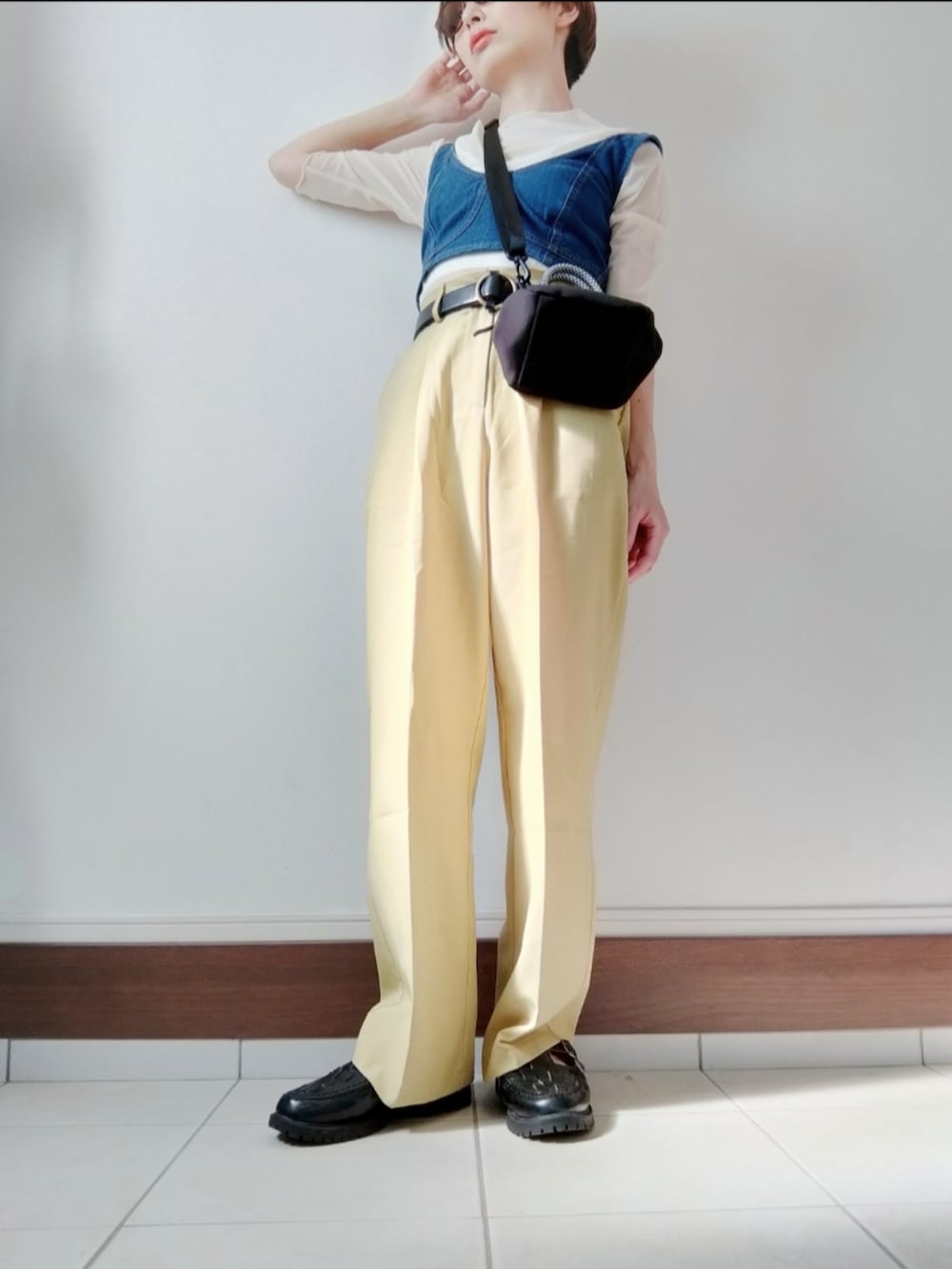 ブルー系のベスト、ブラック系のショルダーバッグ、イエロー系のスラックスを着用したレディースの夏コーディネートの2枚目の写真