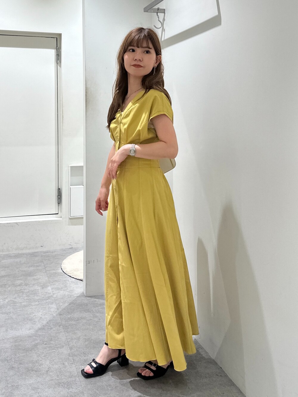 イエロー系のワンピース、ブラック系のサンダル、ホワイト系のショルダーバッグを着用したレディースの夏コーディネートの3枚目の写真
