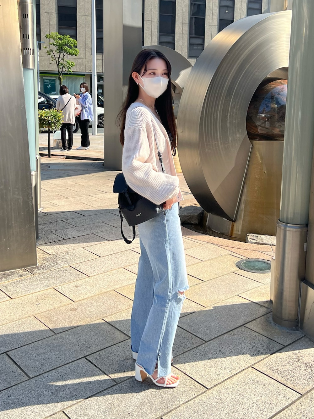 ブルー系のデニムパンツ、ホワイト系のサンダル、ホワイト系のキャミソールを着用したレディースの春コーディネートの2枚目の写真