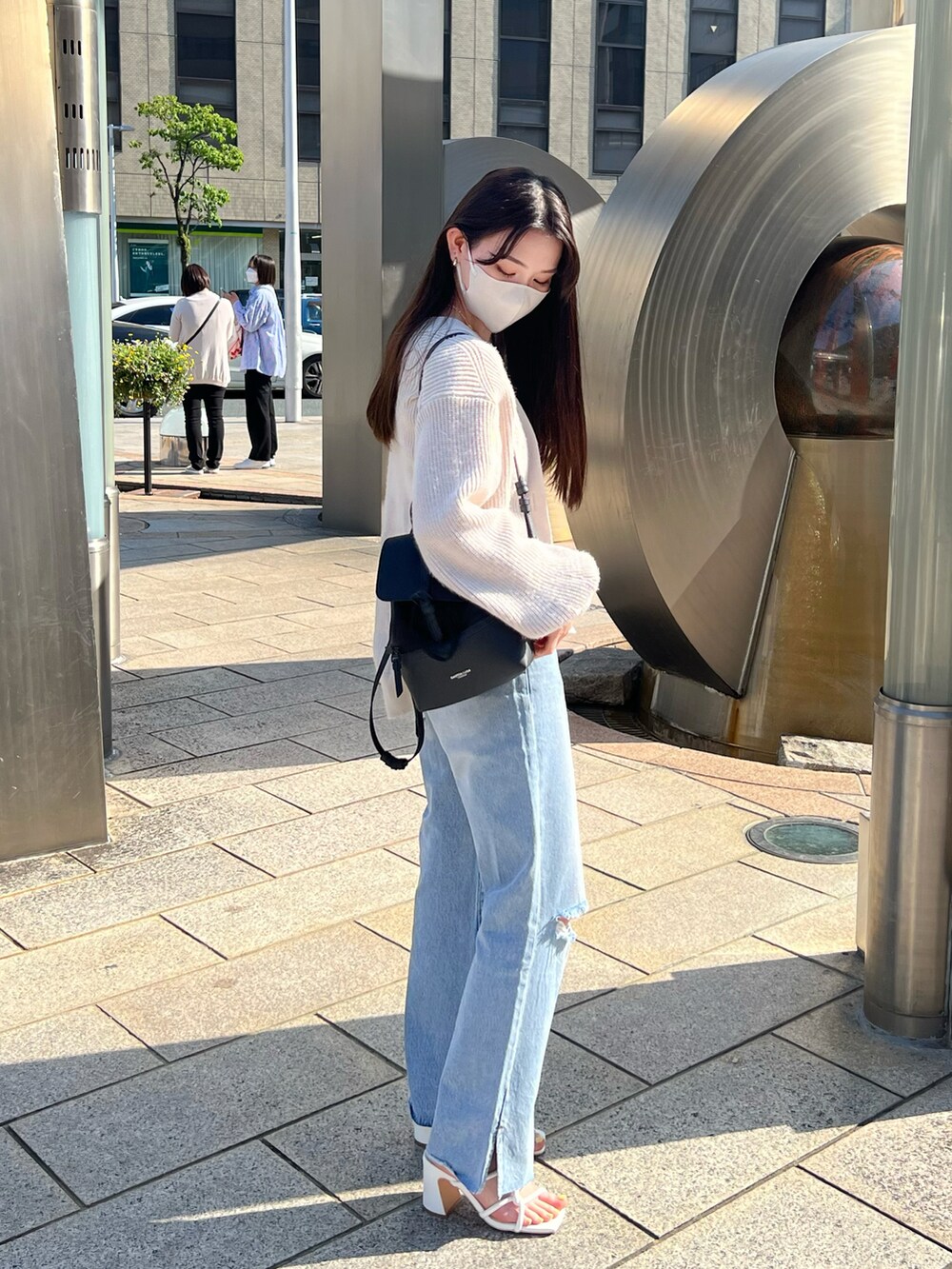 ブルー系のデニムパンツ、ホワイト系のサンダル、ホワイト系のキャミソールを着用したレディースの春コーディネートの3枚目の写真