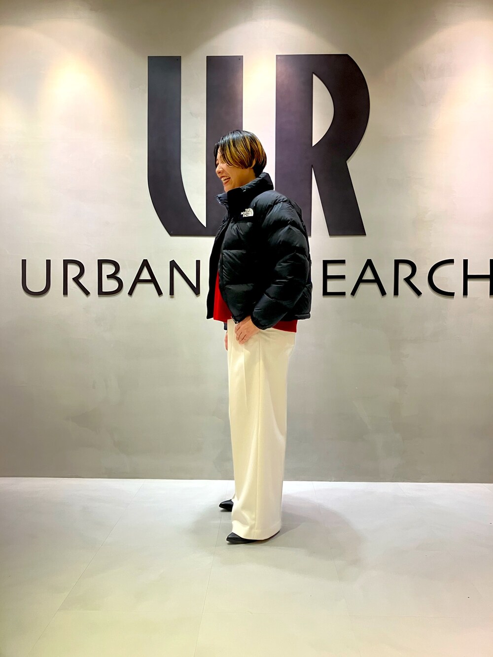 ホワイト系のその他パンツ、レッド系のニット/セーター、ブラック系のダウンジャケット/コートを着用したレディースの秋コーディネートの2枚目の写真