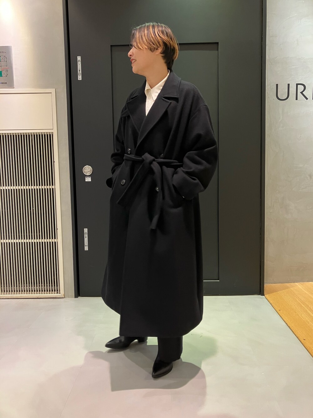 ブラック系のブーツ、ホワイト系のTシャツ/カットソー、ブラック系のチェスターコートを着用したレディースの秋コーディネートの2枚目の写真