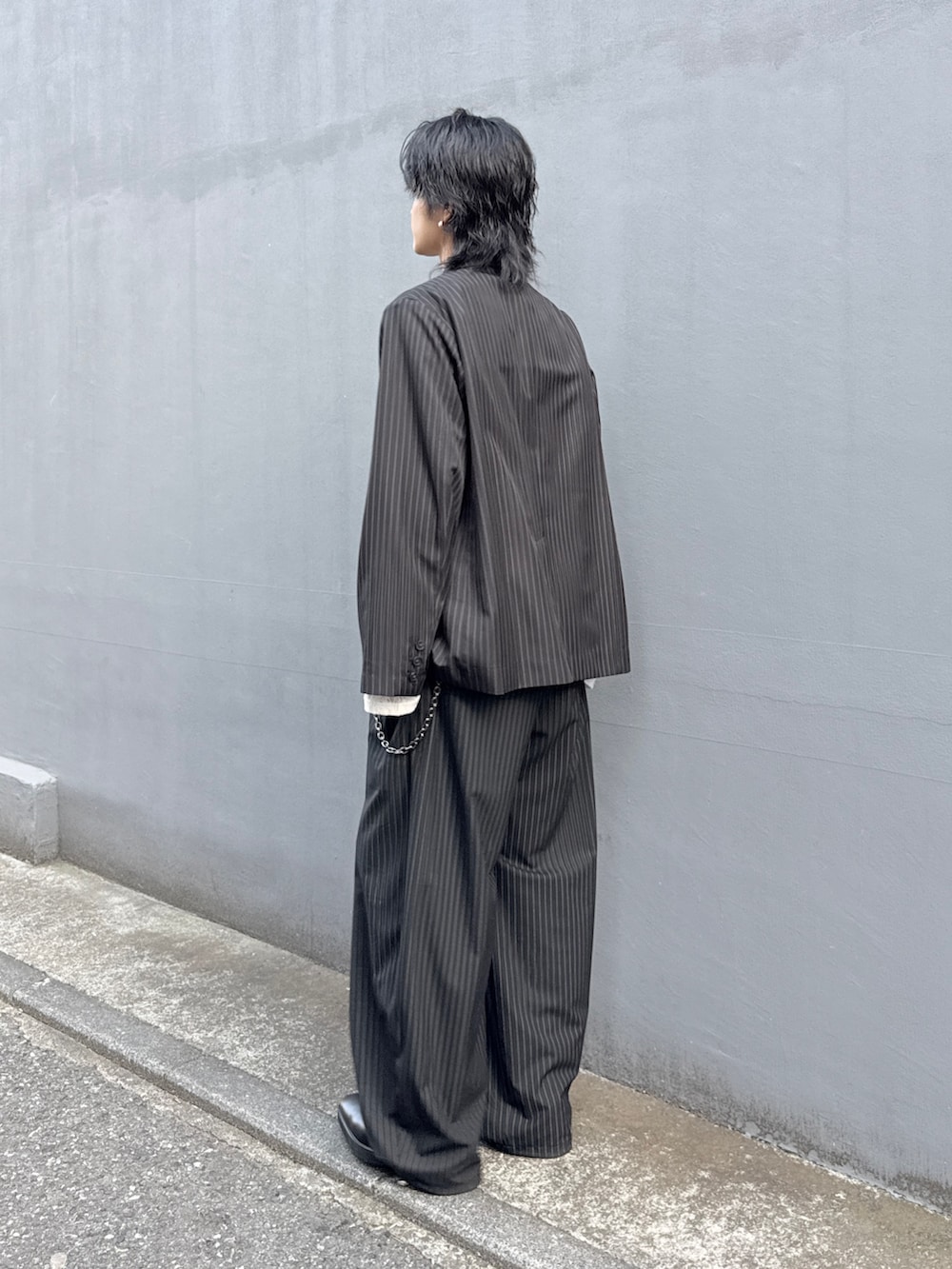 ブラック系のテーラードジャケット、ブラック系のスラックス、ホワイト系のTシャツ/カットソーを着用したメンズの春コーディネートの3枚目の写真