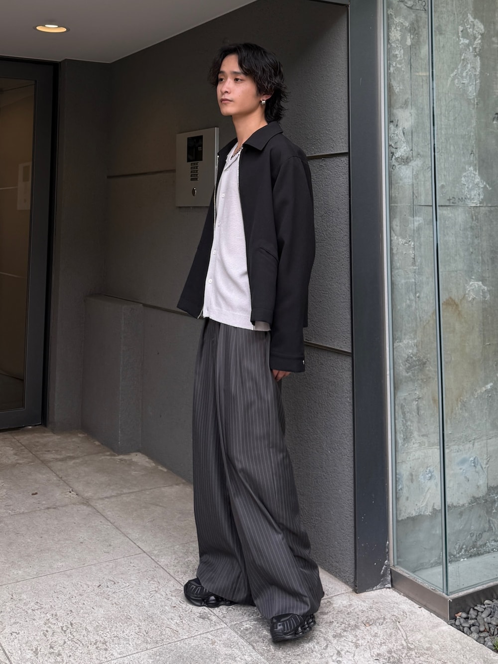 グレー系のスラックス、グレー系のシャツ/ブラウス、ブラック系のブルゾンを着用したメンズの夏コーディネートの3枚目の写真