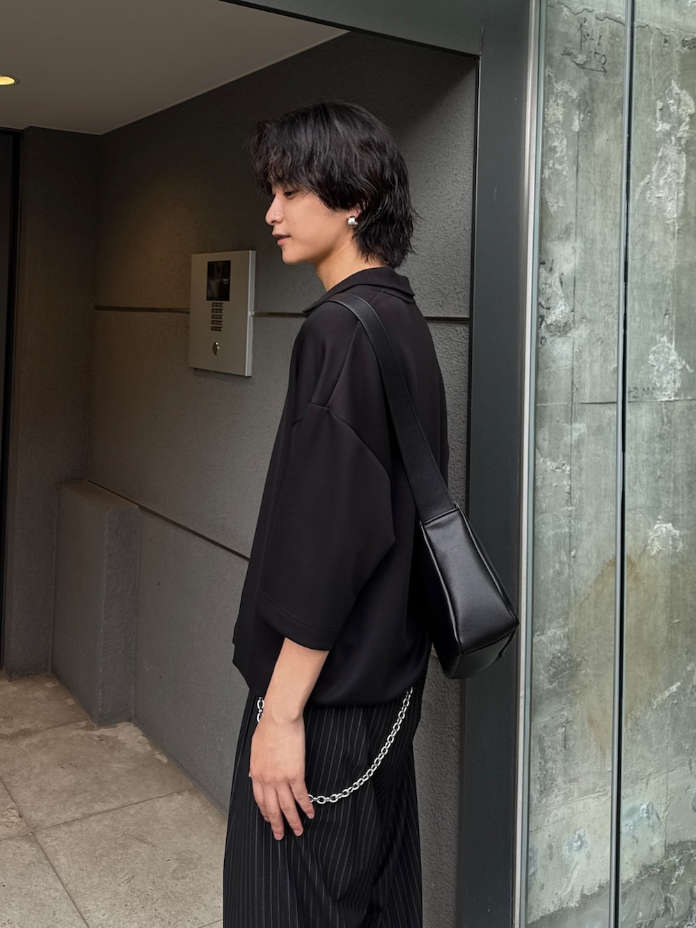 ブラック系のスラックス、ブラック系のTシャツ/カットソー、ブラック系のショルダーバッグを着用したメンズの夏コーディネートの6枚目の写真
