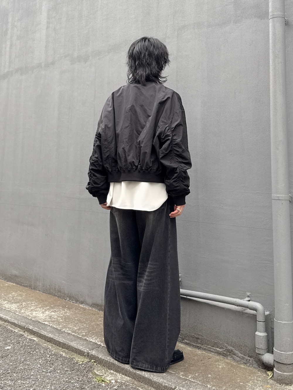 ブラック系のデニムパンツ、ホワイト系のシャツ/ブラウス、ブラック系のMA-1を着用したメンズの春コーディネートの3枚目の写真