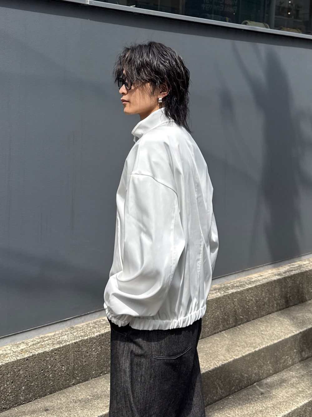 ホワイト系のブルゾン、ブラック系のTシャツ/カットソー、ブラック系のデニムパンツを着用したメンズの春コーディネートの5枚目の写真