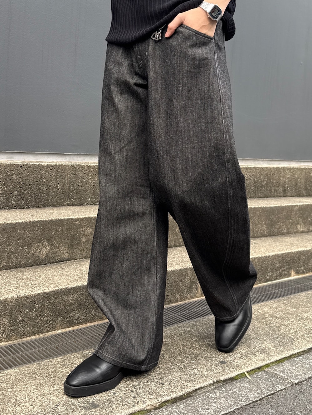 ブラック系のニット/セーター、ブラック系のショルダーバッグ、ブラック系のデニムパンツを着用したメンズの春コーディネートの8枚目の写真