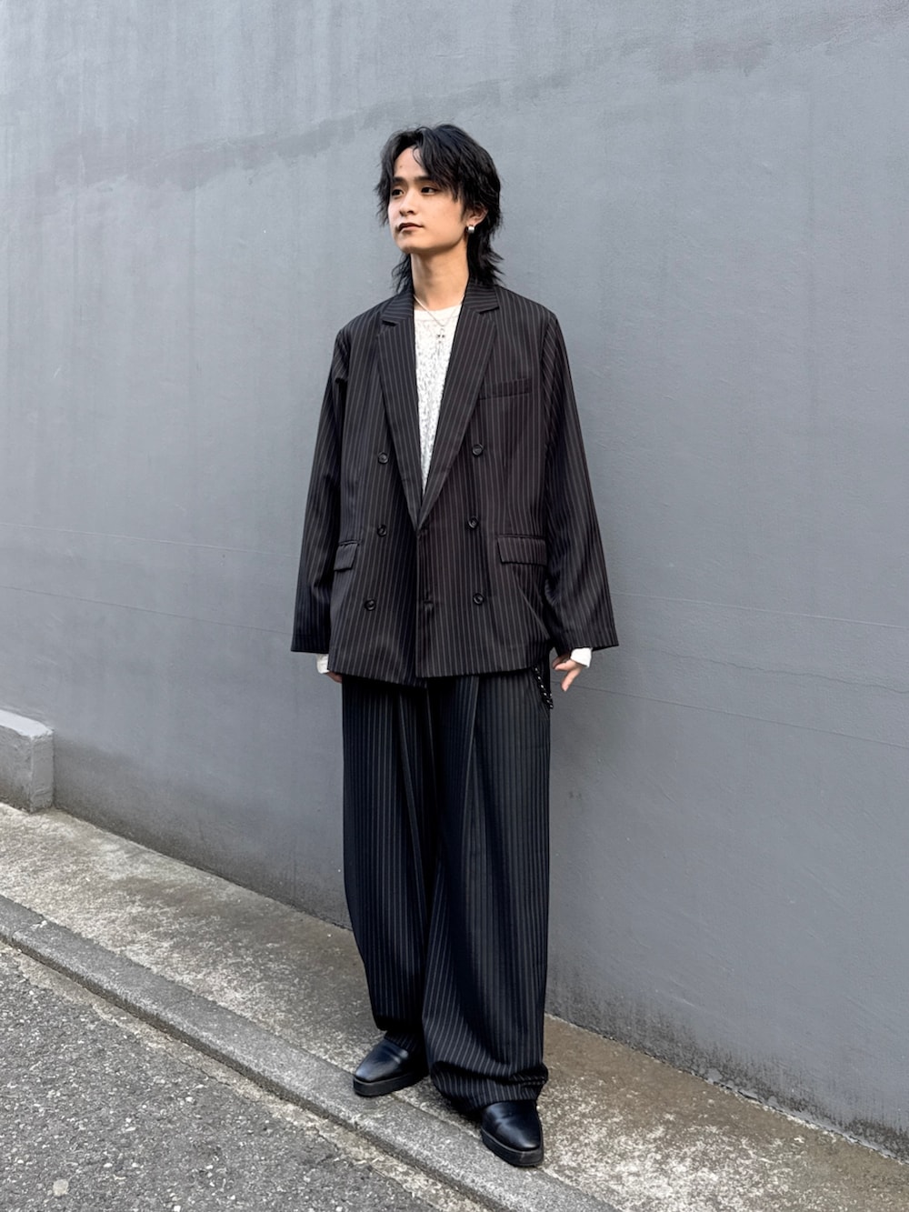 ブラック系のテーラードジャケット、ブラック系のスラックス、ホワイト系のTシャツ/カットソーを着用したメンズの春コーディネートの2枚目の写真