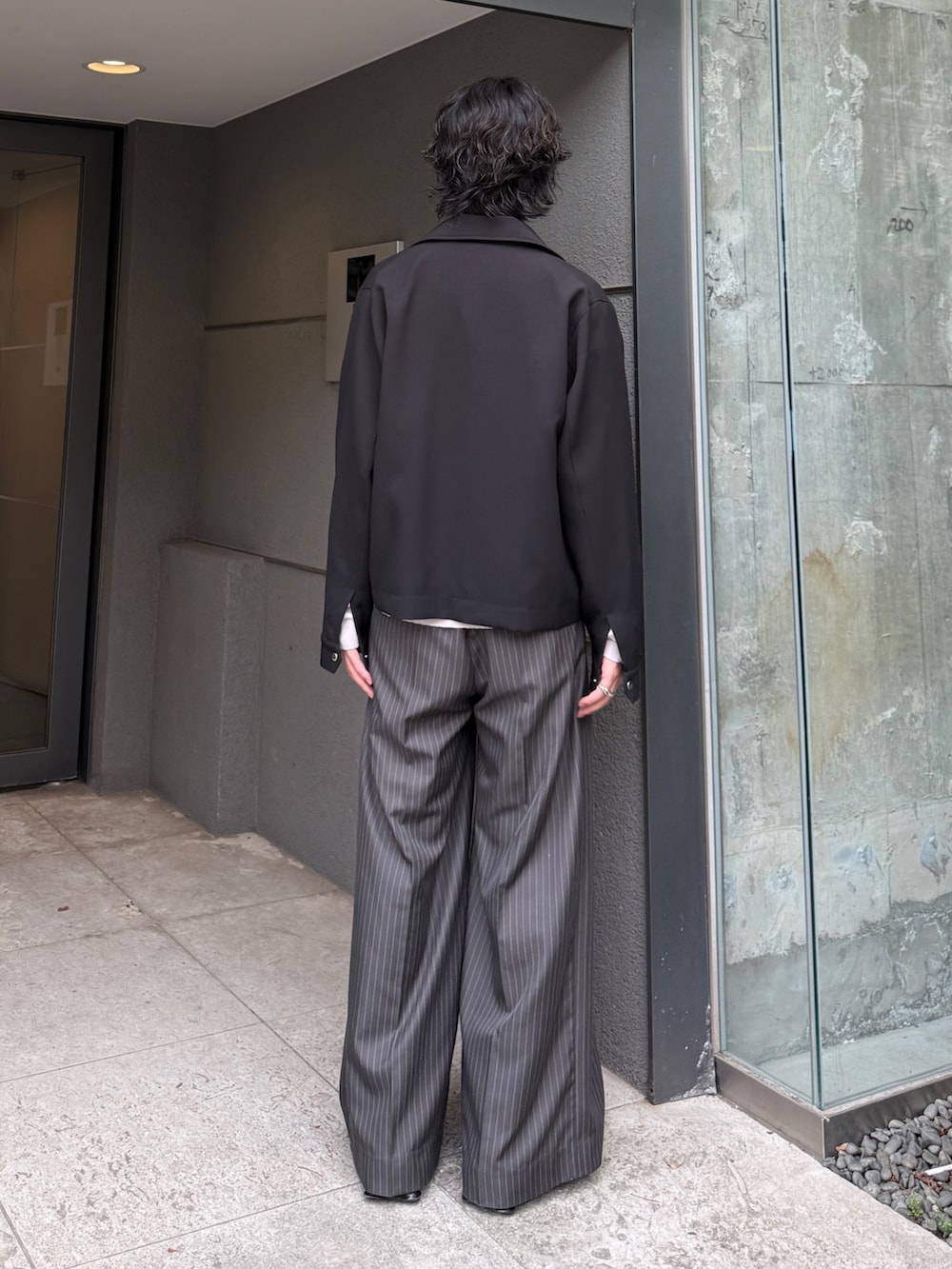 グレー系のスラックス、グレー系のシャツ/ブラウス、ブラック系のブルゾンを着用したメンズの夏コーディネートの4枚目の写真