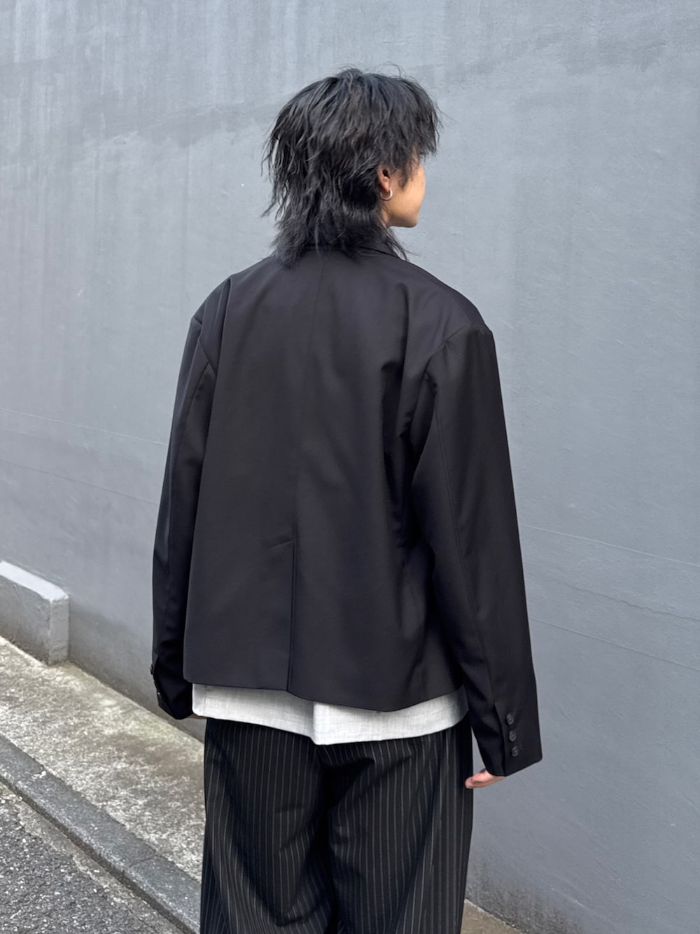 ブラック系のテーラードジャケット、グレー系のシャツ/ブラウス、ブラック系のスラックスを着用したメンズの春コーディネートの6枚目の写真