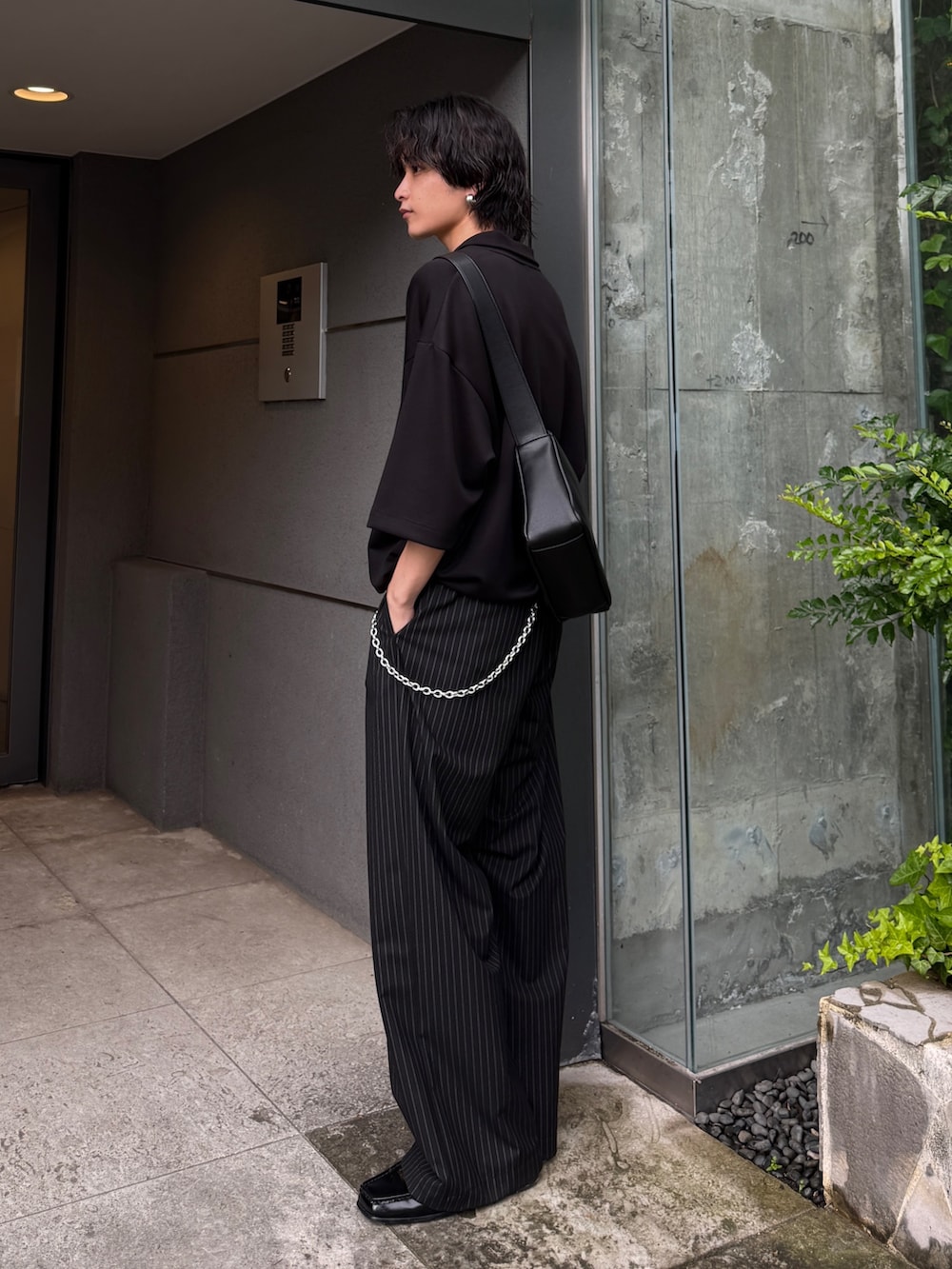 ブラック系のスラックス、ブラック系のTシャツ/カットソー、ブラック系のショルダーバッグを着用したメンズの夏コーディネートの3枚目の写真