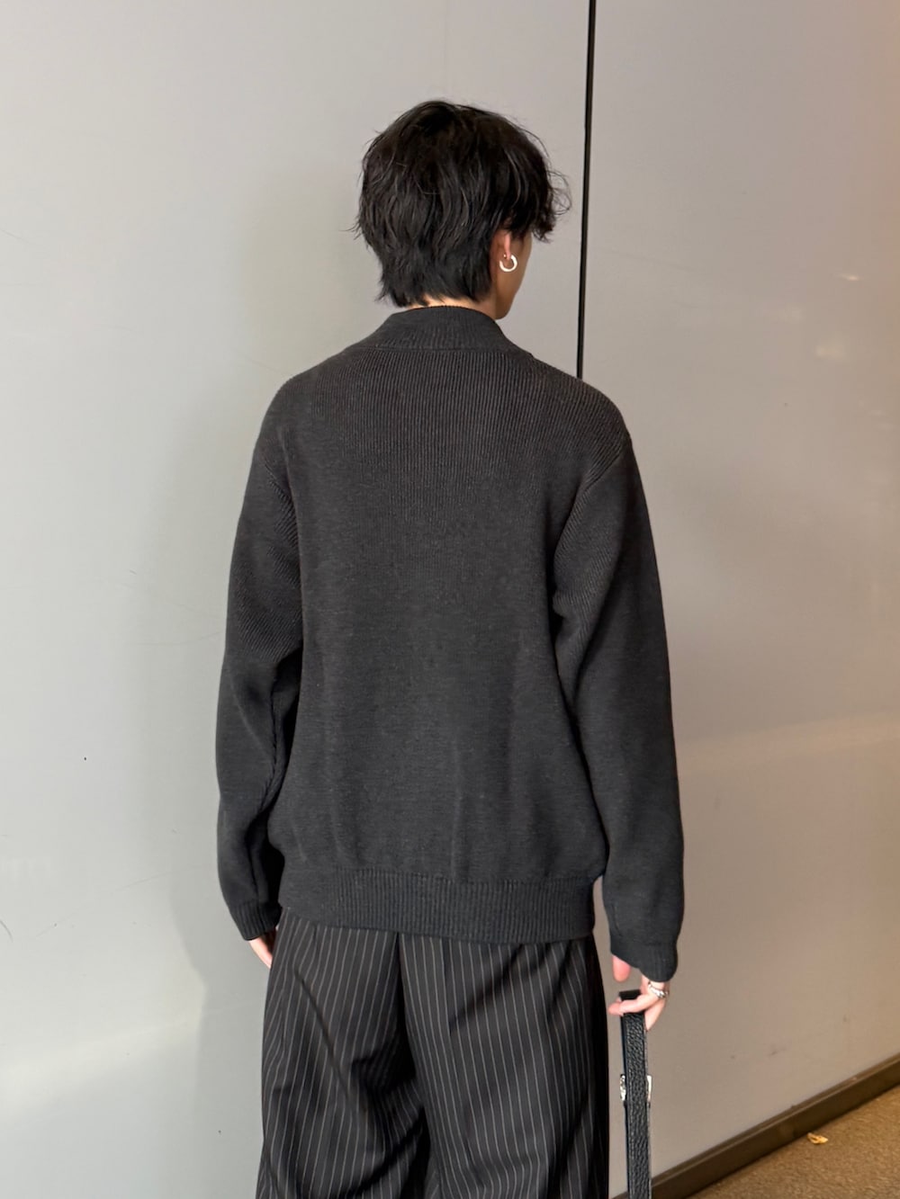 グレー系のニット/セーター、ブラック系のスラックス、ブラック系のショルダーバッグを着用したメンズの秋コーディネートの6枚目の写真