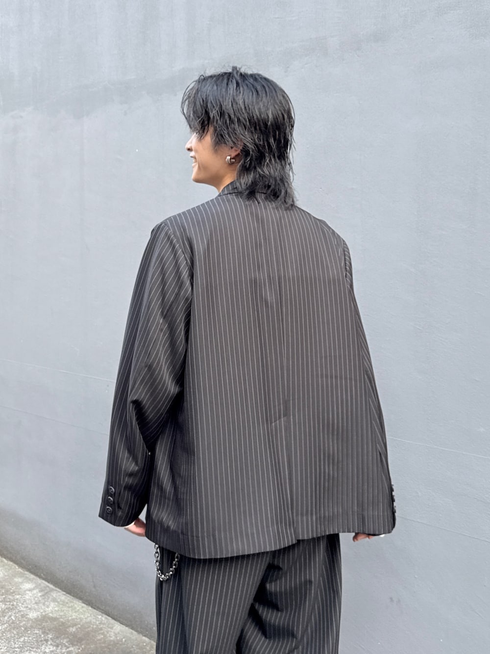 ブラック系のテーラードジャケット、ブラック系のスラックス、ホワイト系のTシャツ/カットソーを着用したメンズの春コーディネートの7枚目の写真