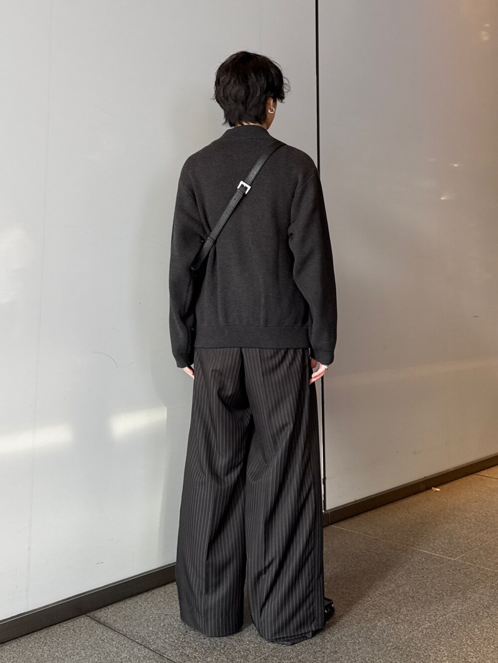 グレー系のニット/セーター、ブラック系のスラックス、ブラック系のショルダーバッグを着用したメンズの秋コーディネートの3枚目の写真