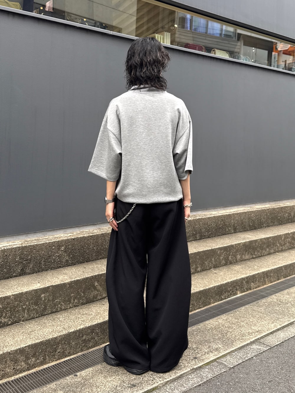 グレー系のTシャツ/カットソー、ブラック系のスラックス、シルバー系のウォレットチェーンを着用したメンズの夏コーディネートの3枚目の写真