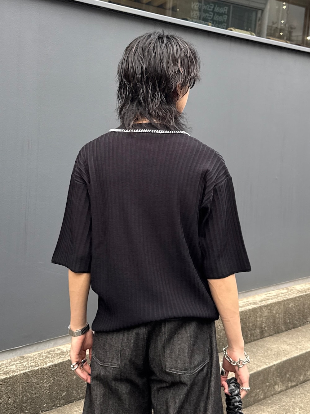 ブラック系のニット/セーター、ブラック系のショルダーバッグ、ブラック系のデニムパンツを着用したメンズの春コーディネートの6枚目の写真